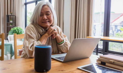 Elder lady sitting in front of laptop and Alexa