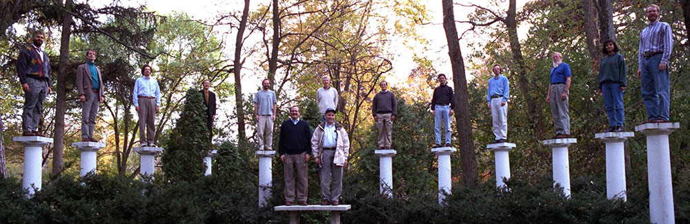 Faculty standing on pillars at a retreat.