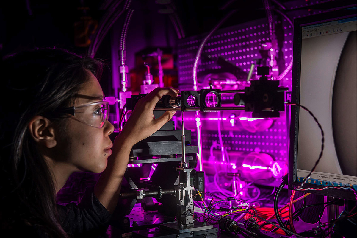 LLE researcher inspecting equipment at workbench