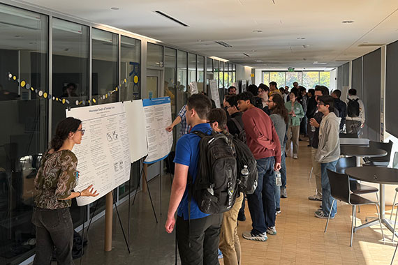 Researchers presenting posters in long hallway