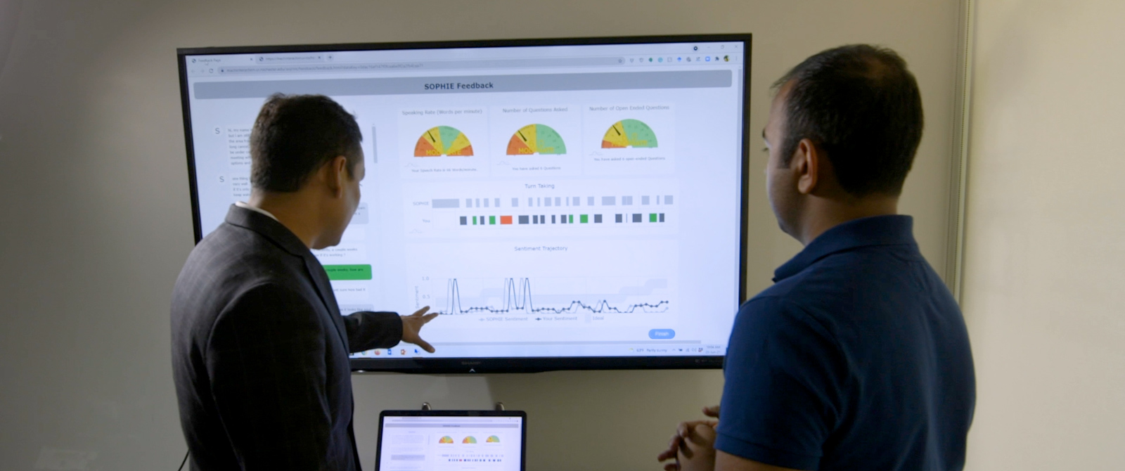 Professor Ehsan Hoque points at an analytics dashboard for the artificial intelligence avatar SOPHIE.