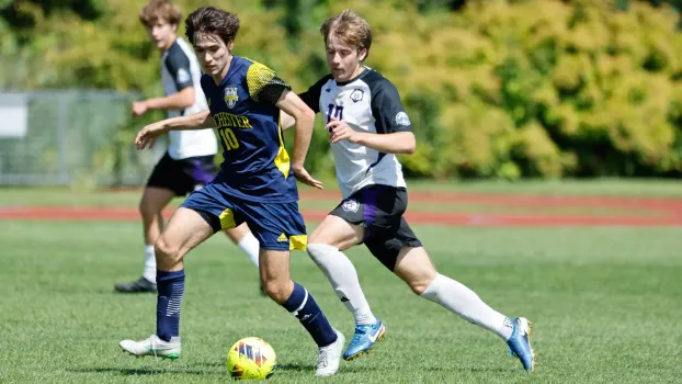 Ashton playing soccer with another player coming up behind him